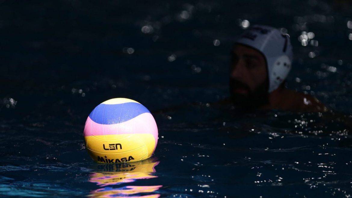 Άνδρας παίζει νερόβόλεϊ με μπάλα σε πισίνα, προετοιμασία για αθλητικό αγώνα.